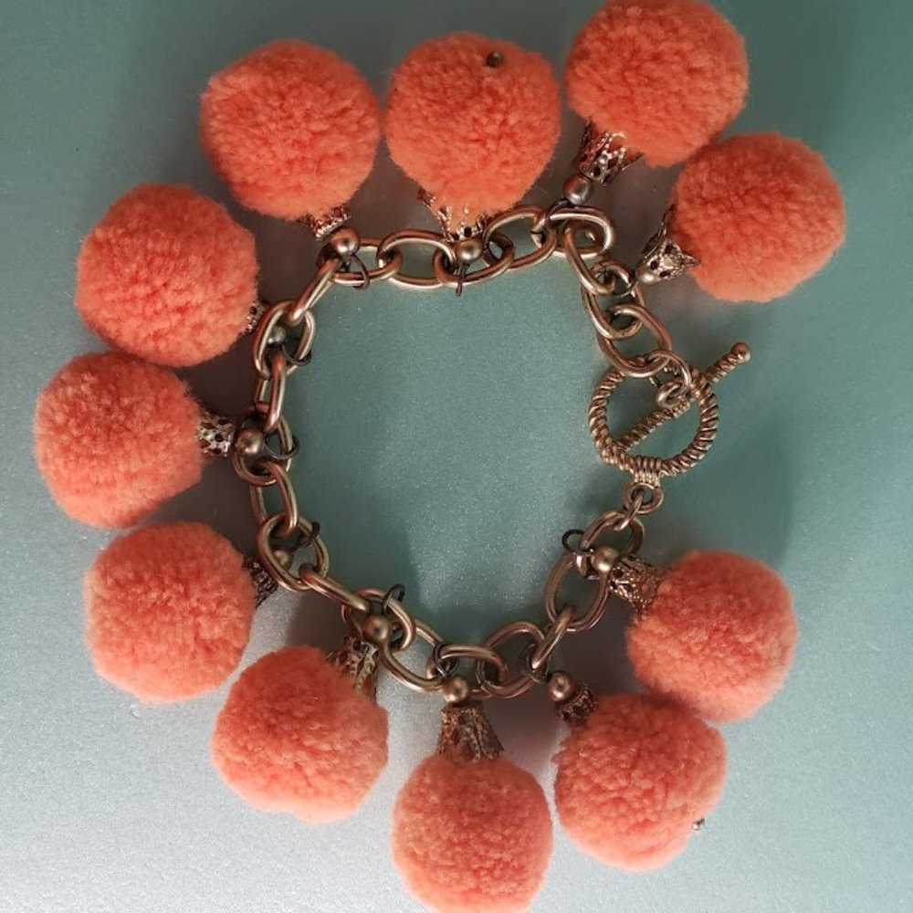 Gold bracelet with 11 orange pom poms - t bar closure